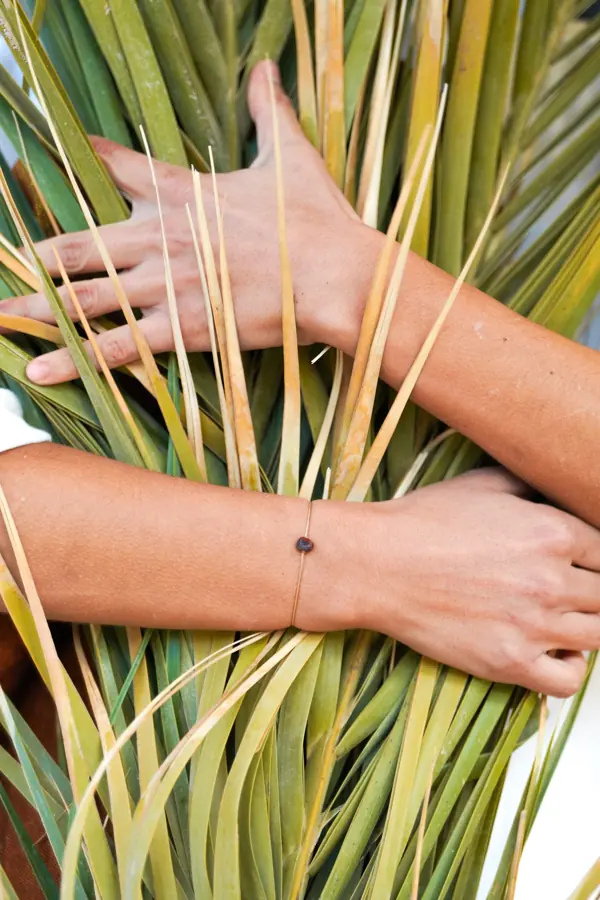 Des mains tressent des feuilles de palmier