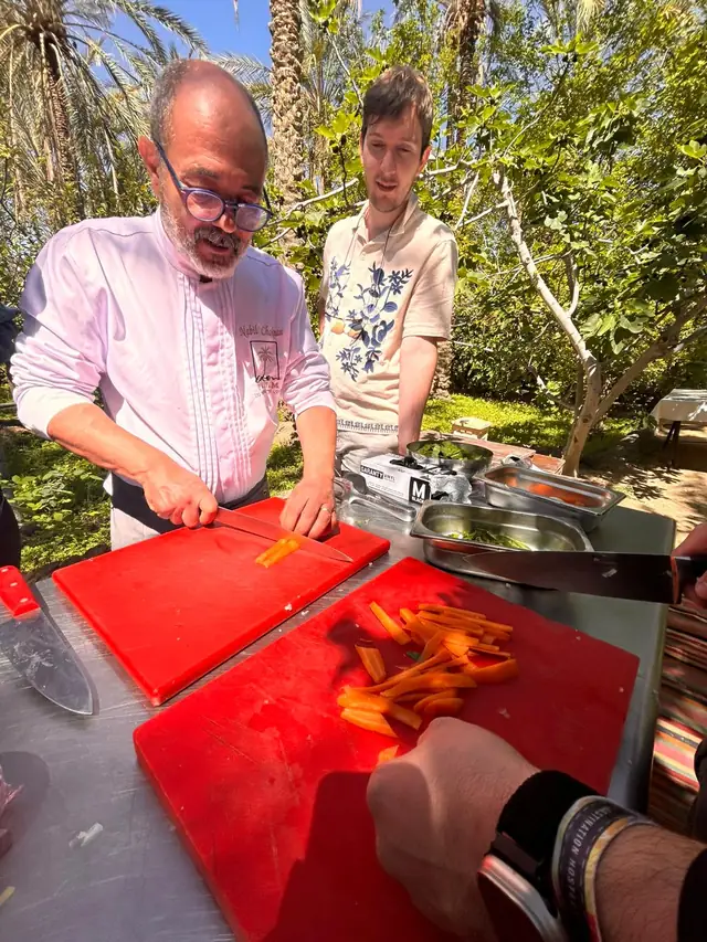 Le chef taille des carottes en bâtonnets sous les palmiers