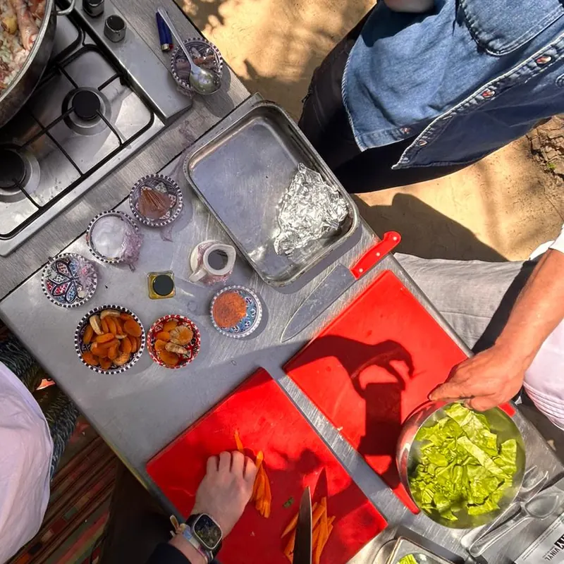 Le plan de travail vu d'en haut : abricots secs et épices dans des bols tunisiens, légumes en cours de découpe