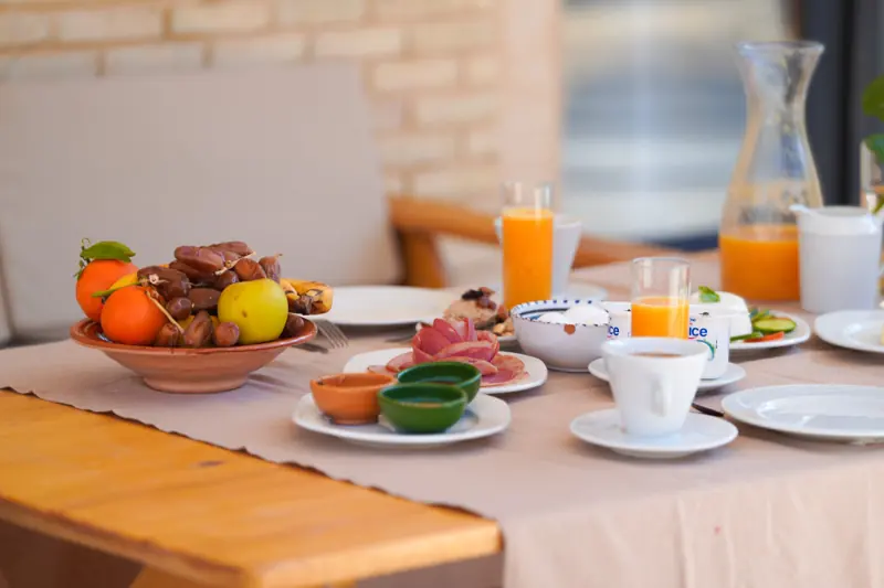 Un petit-déjeuner dressé : fruits, dattes, jus d'orange et café