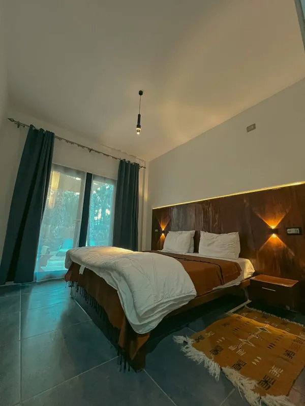 La chambre, avec sa tête de lit en bois de palmier et la porte-fenêtre sur le jardin