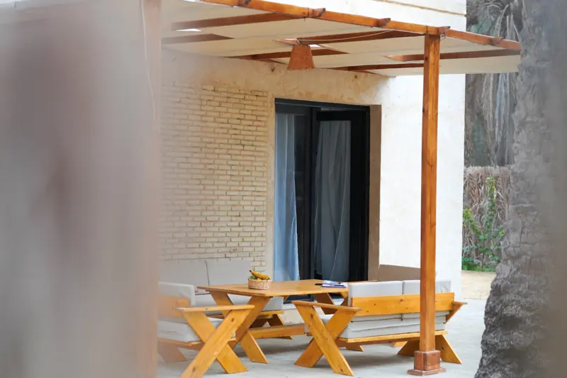 La terrasse privée, avec sa pergola, sa table et ses banquettes en bois