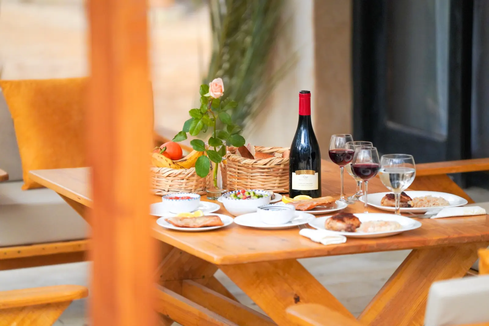 Une table dressée à l'ombre sur la terrasse : salades, fruits, pain et vin